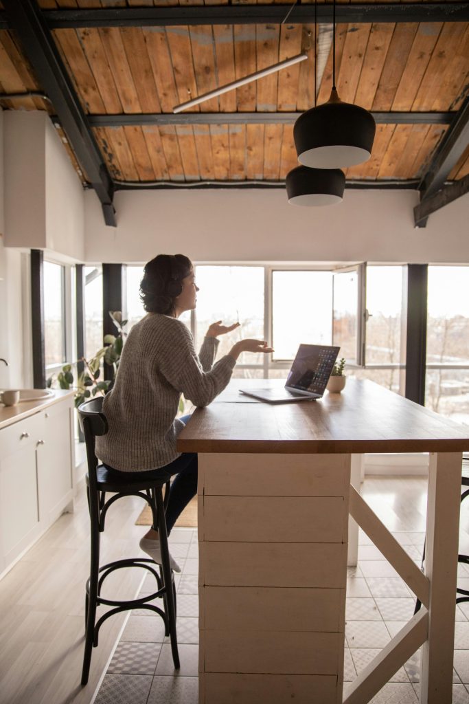 Woman engaged in remote work at home using a laptop. Modern kitchen setting.